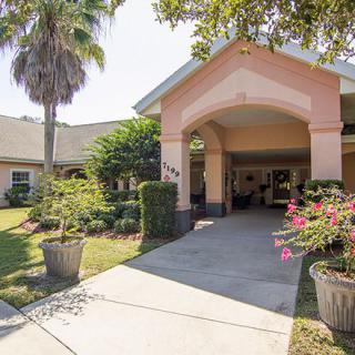 A welcoming entrance of a building surrounded by lush greenery and plants.