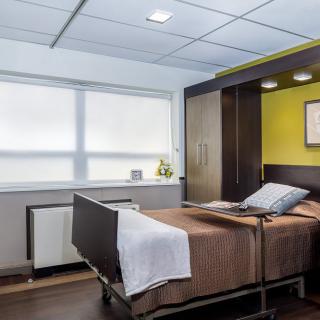 A modern hospital room with a single bed and bright lighting.