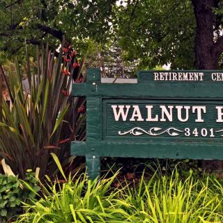Entrance sign for Walnut Retirement Community surrounded by lush greenery.