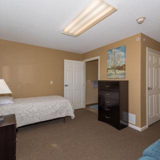 A cozy bedroom with a single bed, dresser, and warm color scheme.