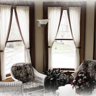 A cozy living room with large windows, elegant curtains, and comfortable seating.