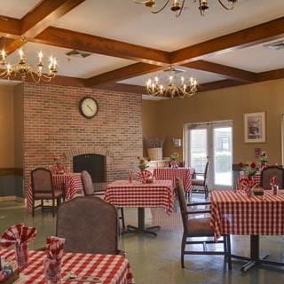 A cozy restaurant dining room with red checkered tablecloths and chandeliers.
