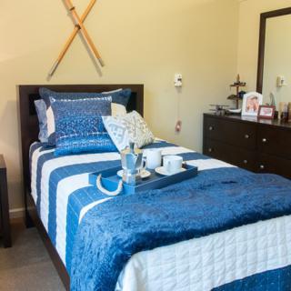 A cozy bedroom featuring blue bedding with modern decor and ski-themed wall art.