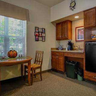 A cozy kitchen nook with a table, chair, and pumpkin decoration next to a compact kitchenette.