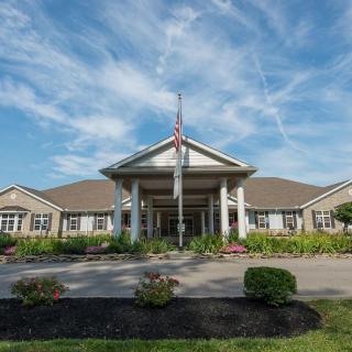 A building with a columned entrance and well-maintained landscaping under a cloudy sky.
