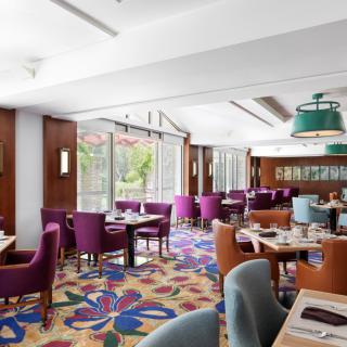 A modern restaurant interior with colorful carpet and ample seating, illuminated by natural light.