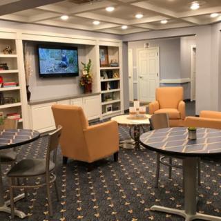 A cozy waiting area with comfortable seating, bookshelves, and a TV.