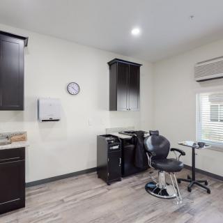 A minimalist hair salon interior with a styling chair, cabinets, and an air conditioner.
