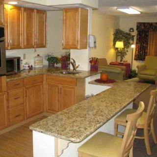 An open-concept kitchen and living area featuring wooden cabinets, a long countertop with bar stools, and cozy seating.