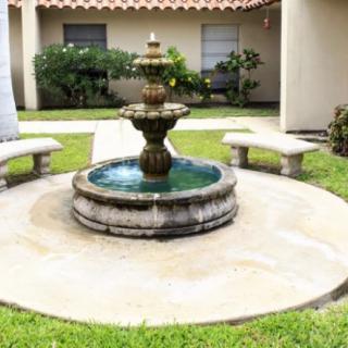 A serene courtyard fountain surrounded by greenery and stone benches.
