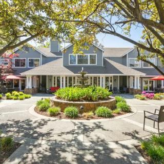 A charming building with a beautifully landscaped garden and trees in the foreground.