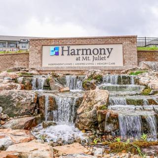 The image shows a landscaped waterfall with a sign for 'Harmony at Mt. Juliet' at the entrance.