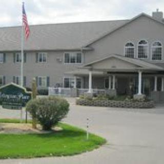 A two-story residential building with a driveway and an American flag in front.