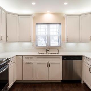 A modern kitchen with white cabinets and stainless steel appliances.