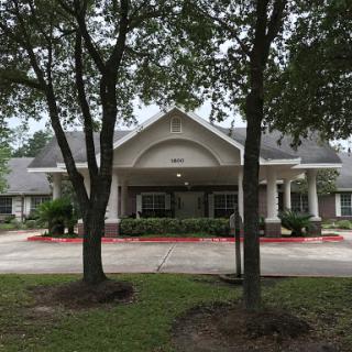 A well-maintained residential building surrounded by lush greenery and a paved driveway.