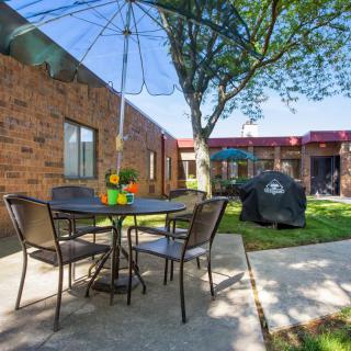 A cozy outdoor patio area with a table, chairs, and an umbrella next to a brick building.
