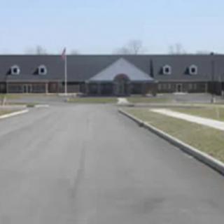 A long driveway leading to a school building on a clear day.