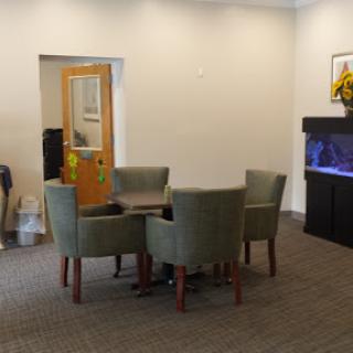 A cozy waiting area featuring a table and chairs, complemented by an aquarium and decorative elements.