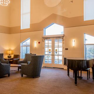 A spacious and elegant lobby featuring a grand piano, comfortable seating, and modern lighting.