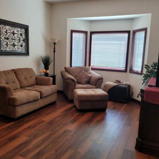 A cozy living room with a couch, armchair, and wood flooring.