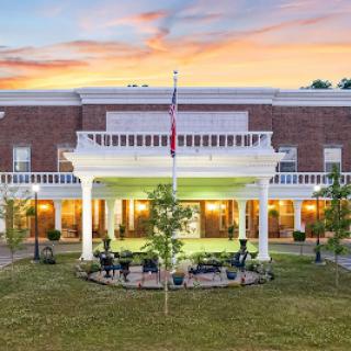 A beautifully landscaped exterior of a building at sunset, showcasing grand architecture and vibrant greenery.