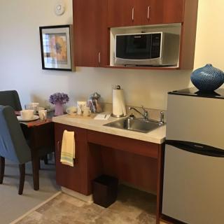 A compact kitchenette with modern appliances and a small dining area.