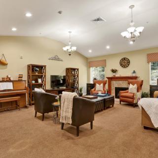 A cozy living room with a piano, comfortable seating, and a fireplace.
