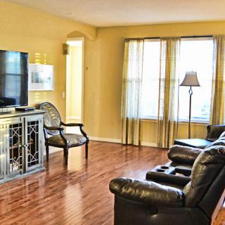 A cozy living room with leather armchairs, a large television, and wooden flooring.