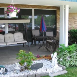 A cozy patio with a swing and outdoor seating area, surrounded by a garden with plants and decorative elements.