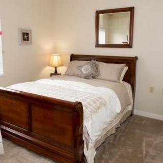 A cozy bedroom with a wooden bed frame and a mirror above it.