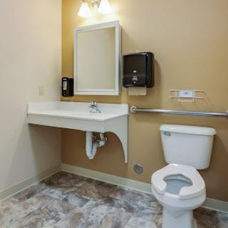 A clean and accessible bathroom featuring a toilet, sink, and hand dryer.
