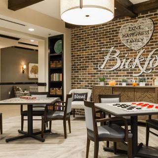 A modern and cozy seating area with tables and chairs, featuring a brick wall and warm lighting.
