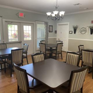 A neatly arranged dining room with several tables and chairs, decorated with a chandelier and wall decor.