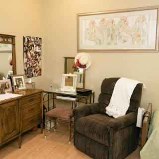 A cozy living room with an armchair, dresser, and decorative elements.