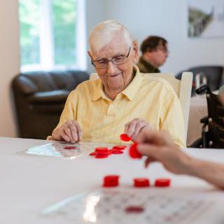 An elderly man playing a game of bingo indoors.