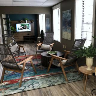A modern living room featuring comfortable seating, a colorful rug, and a television.