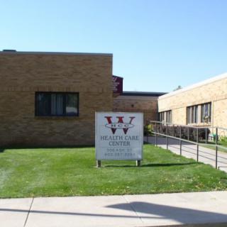 A brick school building with a sign on the lawn.