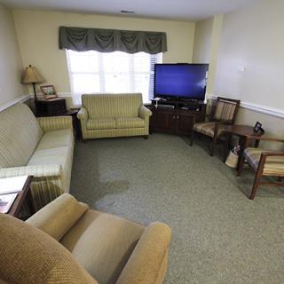 A cozy living room with a sofa, armchairs, and a television.