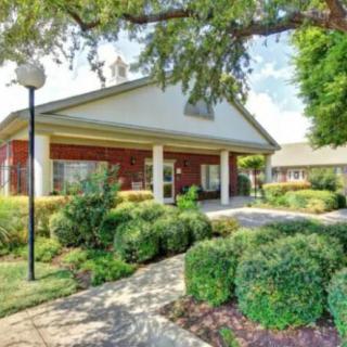 A well-maintained building entrance surrounded by lush landscaping and a paved pathway.