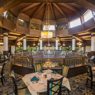 An elegant restaurant interior featuring a central chandelier and well-arranged dining tables.