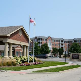 An entrance of an apartment complex with flags and well-maintained landscaping.