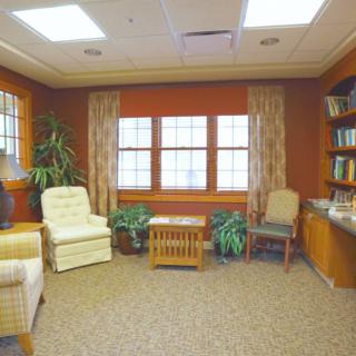 A cozy living room with comfortable seating, bookshelves, and large windows.