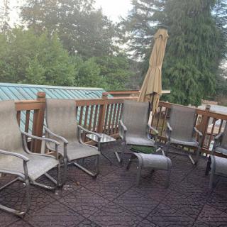 A cozy outdoor patio area with several chairs arranged around a deck.