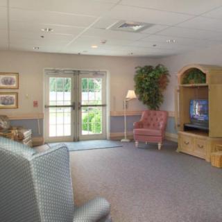A cozy living room with a television, armchairs, and decorative elements.