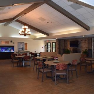 A spacious dining area featuring multiple tables, chairs, a chandelier, and an aquarium.