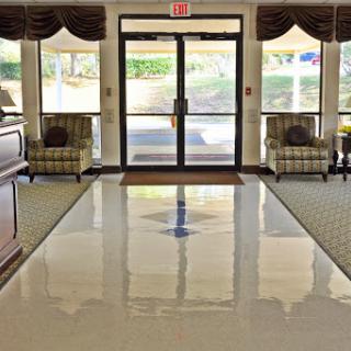 A welcoming lobby area featuring comfortable seating and a polished floor, bathed in natural light from large windows.