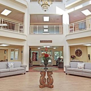 A spacious and well-lit lobby with sofas, a decorative table, and two levels of balconies.