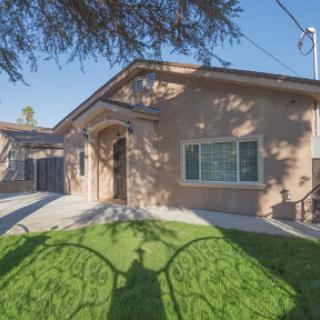 A welcoming residential home surrounded by green grass, with shadows cast on the lawn.