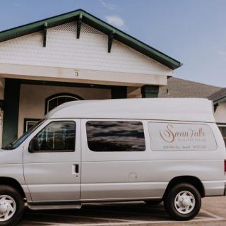 A white van parked in front of a building with signage on the side.