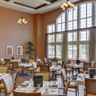 A spacious and elegantly designed restaurant dining area with large windows and neatly arranged tables.